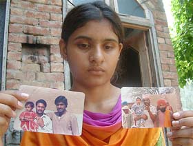 The daughter of Sarabjit Singh holds photographs of her father at Bhikhiwind (Amritsar)