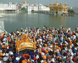 Devotees carry golden palanquin containing Guru Granth Sahib on the occasion of 401 years of the installation of the holy Guru Granth Sahib at Golden Temple in Amritsar on Thursday.