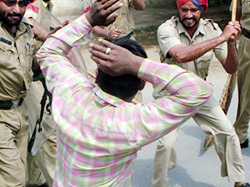 Policemen cane-charge a demonstrator during a protest in Amritsar on Monday. 