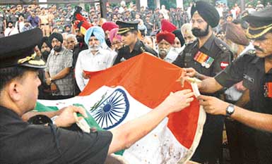 Officers remove the Tricolour from the casket containing the mortal remains of Lieut-Col Amardeep Singh during the officers funeral in Chandigarh on Saturday.