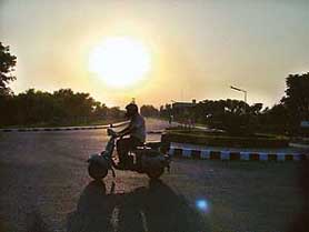 A scooterist drives down the PAU road in the background of an eclipsed sun in Ludhiana on Monday.