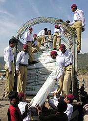 Pakistani workers and an Indian worker transfers quake relief goods from an Indian truck to a Pakistani truck after opening of a crossing point at the Line of Control (LoC) in Gulpur at Poonch, about 250 km from Jammu, on Monday. 