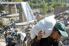Pakistani porters carry bags of relief material following the opening of the Aman Setu bridge, which links India and Pakistan on the Line of Control. The two countries are exchanging the relief material to help the quake-hit people.