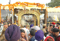 Devotees pay obeisance to Guru Granth Sahib kept in a golden palanquin placed in a specially designed bus at Kundli, on the Delhi-Haryana border, on Sunday. The specially designed bus is travelling from Gurdwara Bangla Sahib in New Delhi to Nankana Sahib, birthplace of Guru Nanak, in Pakistan.
