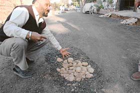 A resident shows a patch of withered road after some days of recarpeting