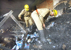 Firemen go through burnt debris following a fire at a clothing factory, in New Delhi, on Wednesday.
