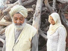 Nambardar Ajmer Singh and Basant Kaur pose near the fuelwood stocked by them for their cremation