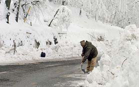 A labourer from the Border Road's Beacon Project uses a shovel to remove ice from a stretch of road at the eastern end of the Jawahar Tunnel, 95 km south of Srinagar, on Thursday.