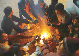 People beat the chill by sitting around a bonfire in Ludhiana on Sunday