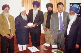 Mr Ajit Singh Badh, CEO, Sher-e-Punjab Radio Canada, hands over a cheque for Rs 11 lakh for quake victims to Mr Khem Singh Gill, vice-president of the Kalgidhar Society, at Bilga village on Monday