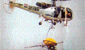 A helicopter with TC-3 bucket slung under it is being used to neutralise an oil slick