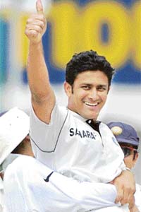Anil Kumble shows the thumbs-up sign as his team-mates celebrate his 500th Test wicket, during the third day of the second Test match between India and England in Mohali