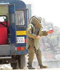 A bomb squad expert carries the explosive in a water bottle found at Byculla station in Central Mumbai for defusing in Mumbai