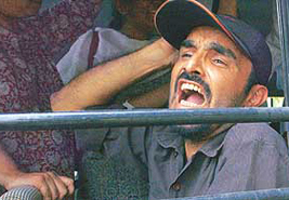 An activist from the Narmada Bachao Andolan (NBA) shouts slogans from a bus as the protesters are transported after being arrested outside Prime Minister Manmohan Singhs residence in