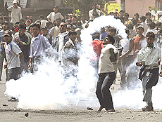 A pro-democracy activist throws a tear gas canister back at riot policemen while defying a curfew in Kathmandu on Monday.