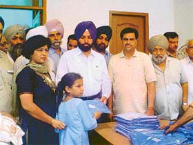 The SP, Traffic, Mr Gurdial Singh, along with councillor Madan Lal Bagga, distributes uniforms to poor schoolchildren in Ludhiana