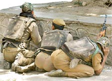 Security personnel take positions behind a wall after militants attacked a public rally in Srinagar on Sunday