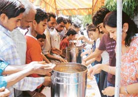 Passersby reach for langar being distributed on the Pakhowal road, in Ludhiana on Friday