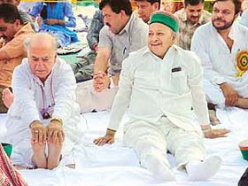 BJP leader Shanta Kumar touches his feet while Himachal Pradesh CM Virbhadra Singh relaxes during the opening day of the seven-day yoga camp at Hamirpur