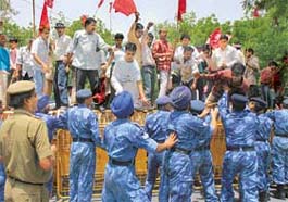Communist Party of India activists shout slogans against the Central Government while standing on a police barricade during a protest against the increase in petrol and diesel prices in New Delhi