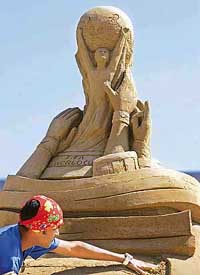 Sudarsan Pattnaik of India works on his sand sculpture, representing the football World Cup trophy on Monday during the fourth international sand sculpture festival Sandsation in Berlin. 