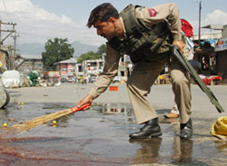 A Jammu and Kashmir Police jawan washes off blood stains from the site where militants shot dead a Head Constable in Srinagar on Friday.