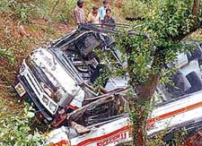 Rescue workers search for the injured in the mangled remains of the bus which rolled down the hill slope near Shimla on Friday