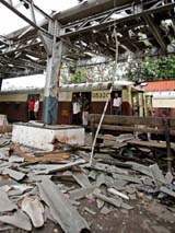 A train passes by a railway platform damaged in Tuesdays bomb blast in Mumbai 