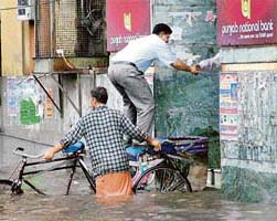 A man climbs on to a rickshaw to enter a bank after heavy rain flooded several areas in Amritsar.