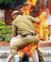 A policeman tries to douse the flames off Rajnish Kumar to prevent him from self-immolation in New Delhi