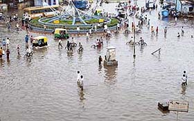 People and vehicles move through a flooded street after a heavy rainfall in Ahmedabad