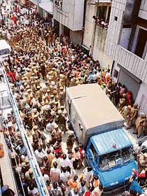 Policemen, mediapersons and residents gather outside the house of Om Parkash, who was found dead along with his wife Santosh and five children, in New Delhi on Monday.