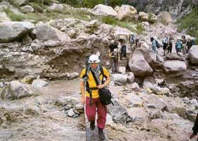 Foreign tourists cross the Raldang nullah near Ribba village of Kinnaur district on a wooden log as the concrete bridge situated on the Hindustan-Tibet road was washed away in flash floods