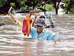 People wade through a flooded road in Surat, about 260 km south of Ahmedabad, on Tuesday. Swirling floodwaters inundated several towns and cities in western and southern India on Tuesday as the military deployed helicopters and boats to help hundreds of thousands of marooned people.