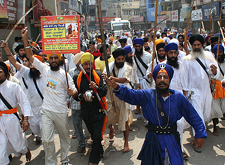 Activists of Sikh organisations brandish swords and raise slogans during a protest against the cutting of hair of a Sikh youth, in Amritsar on Thursday