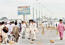 People walk on a rock-littered key highway which was blocked by angry Baluchis during a protest in Hub on Wednesday. 