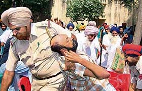 Policemen take away protesting pharmacists from the venue of a medical camp organised at Goniana Mandi