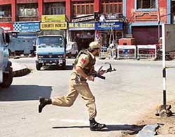 A policeman runs for cover during a militant attack on a CRPF camp at the Akhara building in Srinagar on Wednesday. 