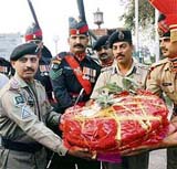A BSF official presents a basket of sweets and fruits to his Pakistani counterpart, on the occasion of Divali, at the Wagah border in Amritsar on Sunday.