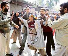 Policemen try to pacify the Kashmiri woman whose husband and son were allegedly killed by a police vehicle in Srinagar on Tuesday. 