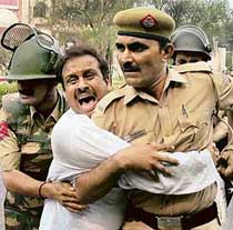 Policemen arrest a trader protesting against the MCD sealing drive, in New Delhi on Monday.