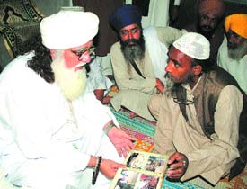 Makhdoom Chan Pir Qadri leafs through the album of mosque pictures. — Photo by Rajiv Sharma