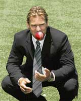 Australia’s Shane Warne tosses a ball as he squats on the turf of the Melbourne Cricket Ground after announcing his retirement from cricket at a news conference on Thursday