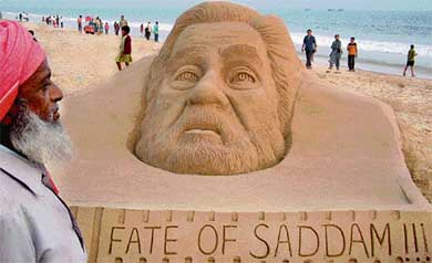 A bystander looks at a sand scuipture of Saddam Hussain on the beach at Puri