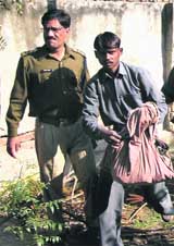 A man carries some of the body parts and skeletons of children retrieved from the backyard of a house at Nithari village near Noida Sector 31, on Friday