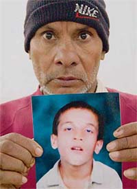 Jeewan Kumar shows the picture of his son Kewal, who went missing from Mani Majra in February 2001