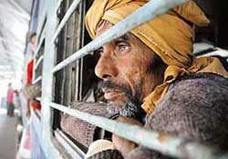 A migrant labourer looks out of a window as he waits in a train compartment in Guwahati on Tuesday. Huddled in buses, trucks and trains, thousands of poor migrant labourers fled Assam on Tuesday, triggered by the killing of scores of workers by militants. 