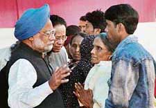 Prime Minister Manmohan Singh talks with relatives of victims of attacks on migrants in Assam at Musaldhari in Tinsukia district of upper Assam on Tuesday