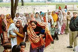 Women with children wait to cast their votes at Hussainpur Choula village in the Dakala Assembly segment. 