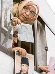 A woman and other passengers show pictures of their missing relatives from a bus window in Srinagar